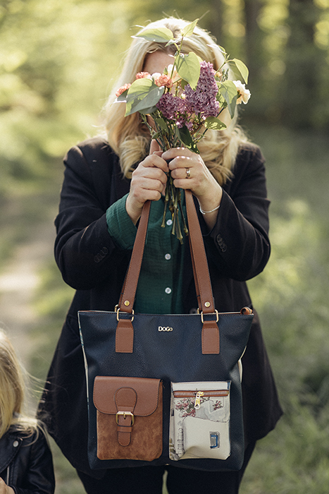 Frau hält Blumenstrauß vor ihrem Gesicht. Eine DOGO Tasche baumeln von ihrem Handgelenk.