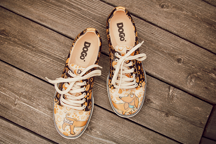 Sneaker der Marke DOGO mit Dackelmotiv auf einem Untergrund aus Holz
