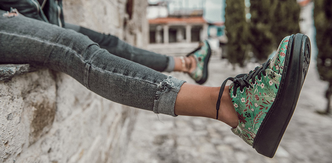 Abbildung bunter Sneaker für Damen mit Plateausohle, die von einer Frau in die Luft gestreckt werden.