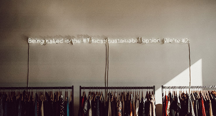 Bild eines Second Hand Shops für bewussten Konsum mit dem Leuchtschriftzug "Being naked is the #1 most sustainable option. We're #2."