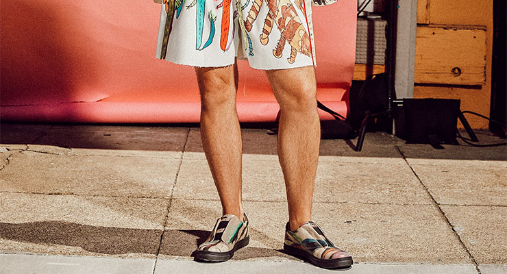 Die DOGO x Creativity Explored Kollektion hat beispielsweise diese Halbschuhe hervorgebracht. Bild von Männerbeinen mit bunt bedruckter Hose und Schuhen aus der DOGO x Creativity Explored Kollektion