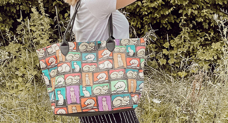 Um das bunte Muster deiner DOGO-Tasche zu schonen, empfehlen wir dir, die Tasche nur mit einem feuchten Tuch zu reinigen. Frau mit kunterbuntem Weekender mit Katzenmotiv