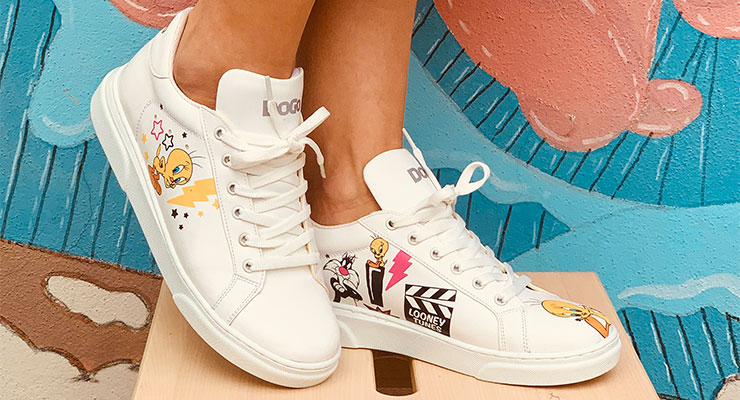 Dass bunte Sneaker genauso gut schlicht sein können, beweisen die neuen DOGO Ace Sneakers. Schlichte DOGO-Schuhe mit Tweety-Motiv werden vor einer bunt bemalten Wand präsentiert.