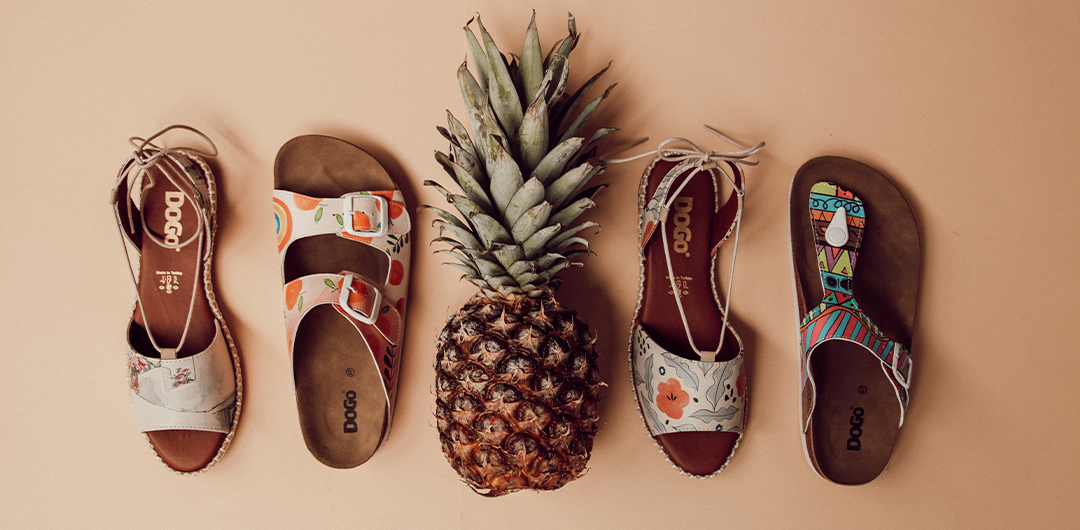 Bunte DOGO Sandalen liegen neben einer Ananas. Sie zählen zu den Sandalen Trends 2022