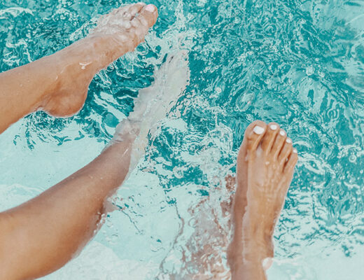 Nackte Frauenbeine baumeln im Wasser eines Swimmingpools