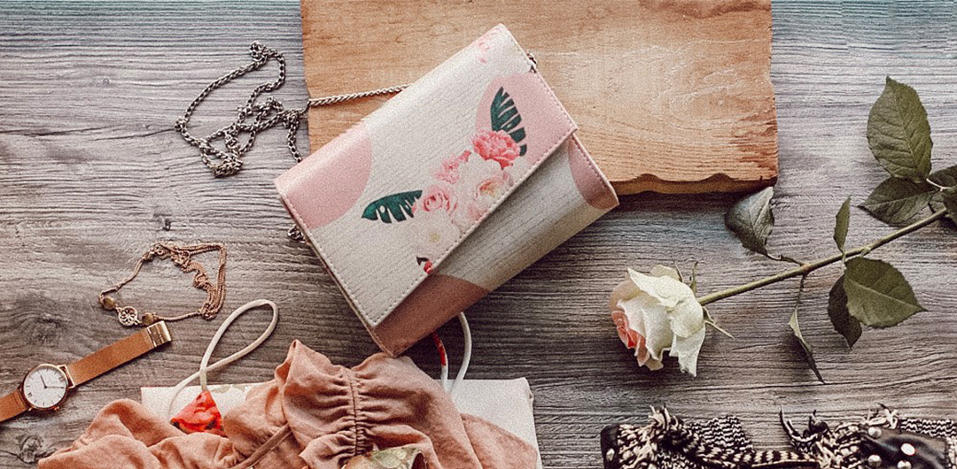 Rosa Clutch mit Blumenprint von DOGO auf einem Tisch