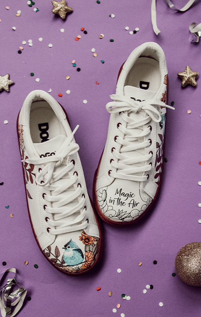 DOGO Ace Sneaker liegen auf einem lila Boden voller Konfetti und Luftschlangen