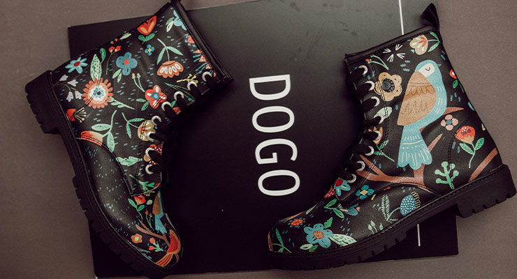 Neue, limitierte Boots aus der DOGO Black Edition im Design Flowers and Birds liegen auf einem schwarzen Schild mit der Aufschrift DOGO.