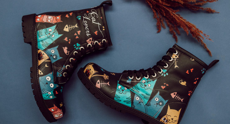 DOGO Boots in der Black Edition im Design Cat Lovers liegen auf blauer Pappe