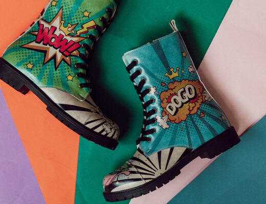 Bunte DOGO Boots mit der Aufschrift WOW und DOGO liegen auf einem bunten, regenbogenfarbenen Untergrund.
