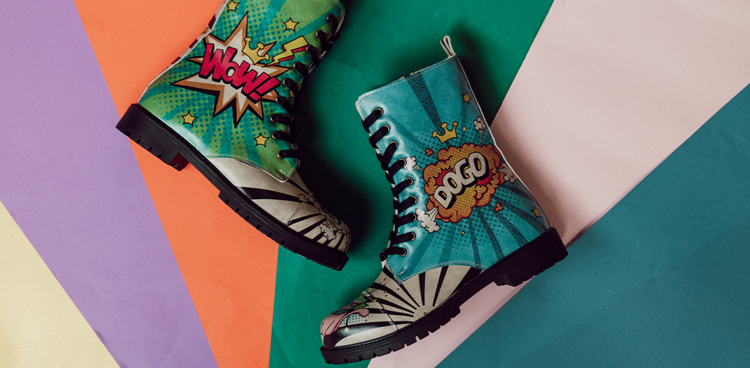 Bunte DOGO Boots mit der Aufschrift WOW und DOGO liegen auf einem bunten, regenbogenfarbenen Untergrund.